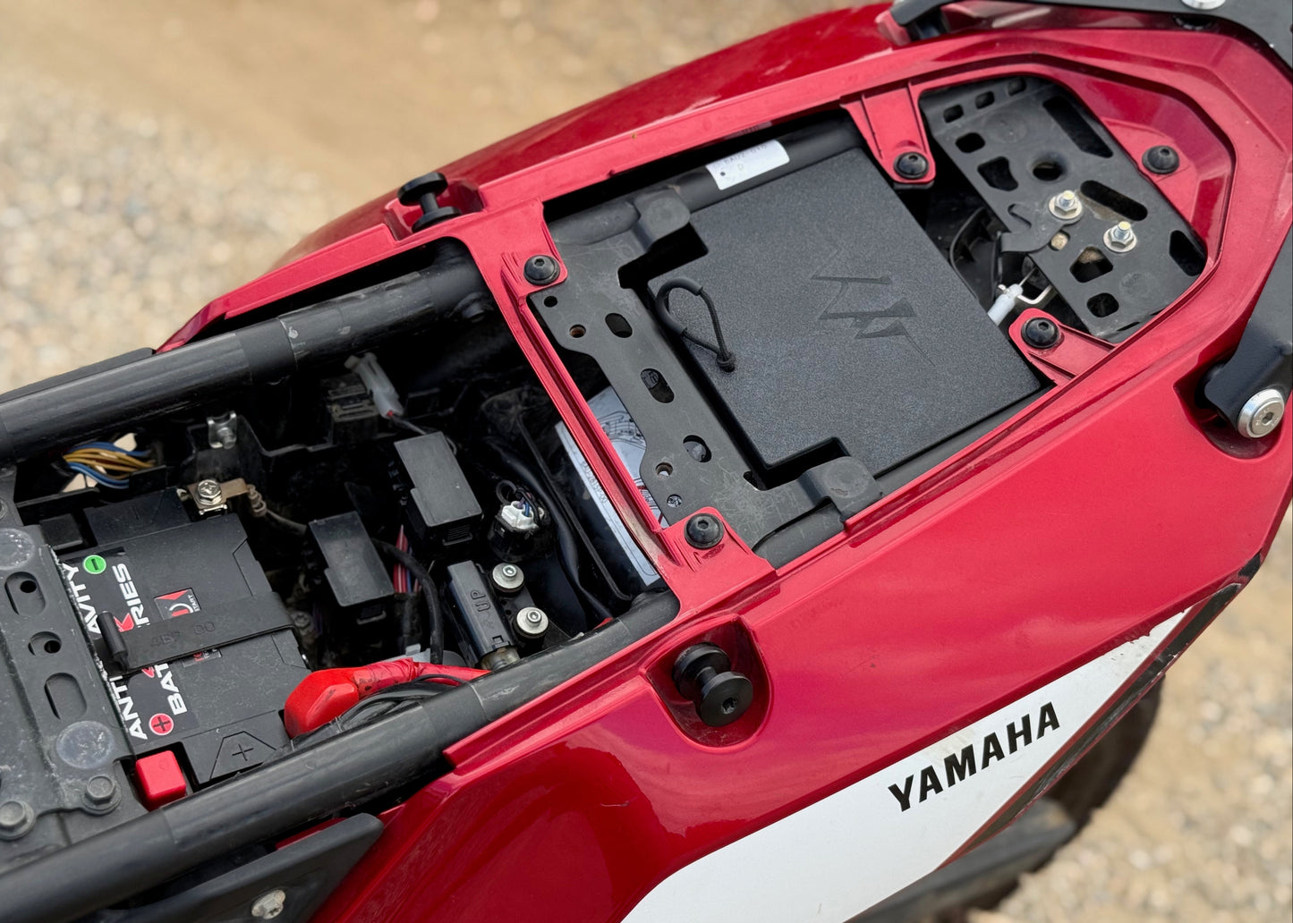 MotoCubby Drifter pillion storage in the rear of a Yamaha Ténéré 700 — wide view showing battery area and seat layout