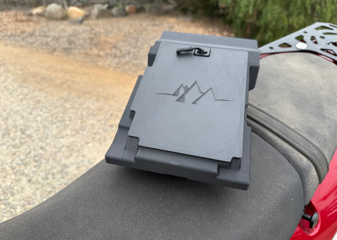 MotoCubby Nomad under-seat storage box installed on a Yamaha Ténéré 700 — top view with seat removed showing the M-mountains embossed lid