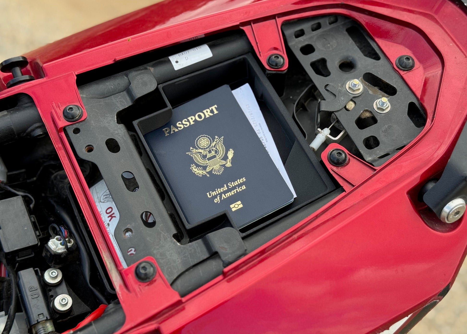 MotoCubby Drifter under-pillion storage on a Yamaha Ténéré 700 — showing a US passport fits inside the compartment