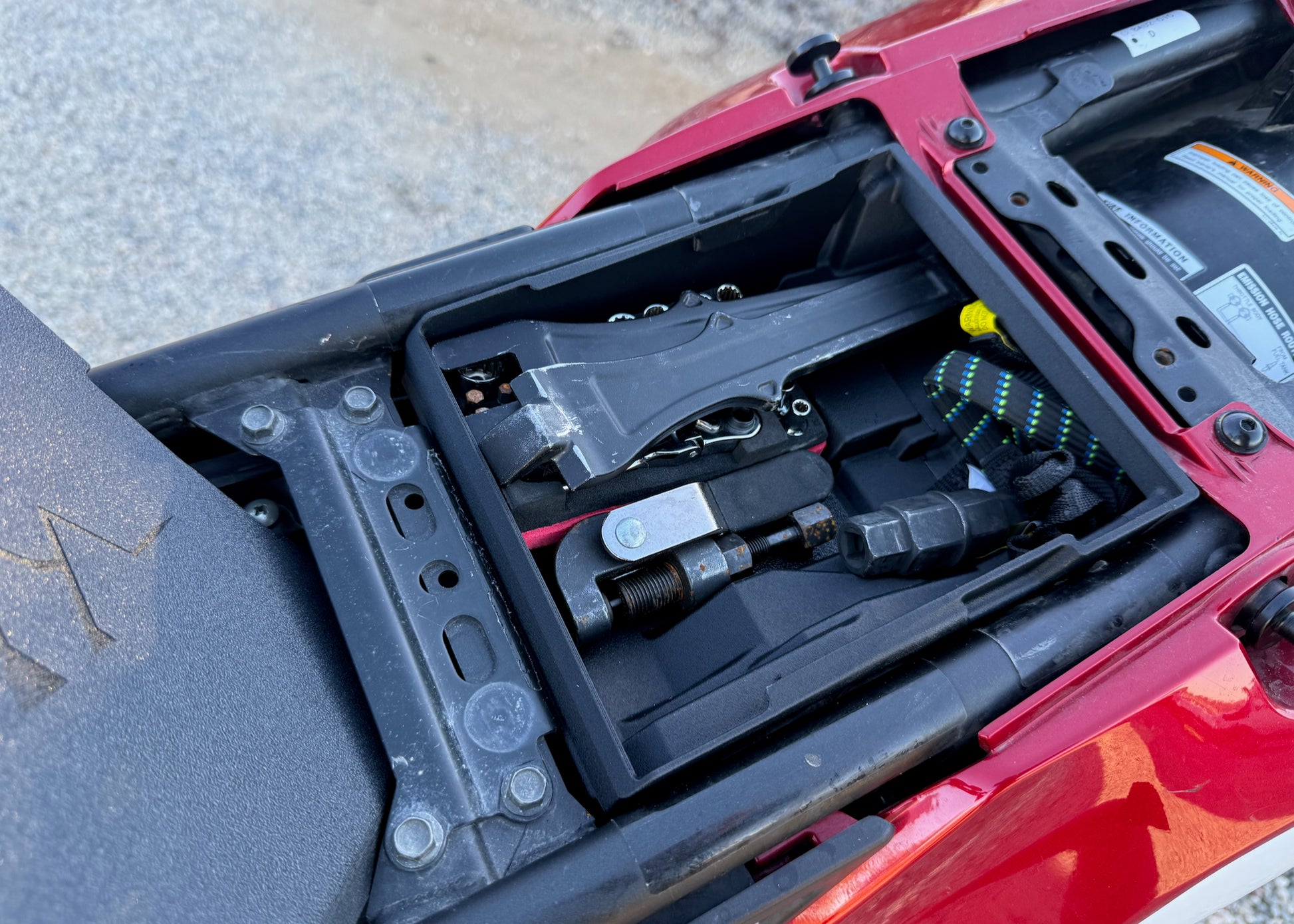 MotoCubby Scout for Yamaha Ténéré 700 Rally seat — close-up of OEM tools secured in the factory tool tray next to the Scout
