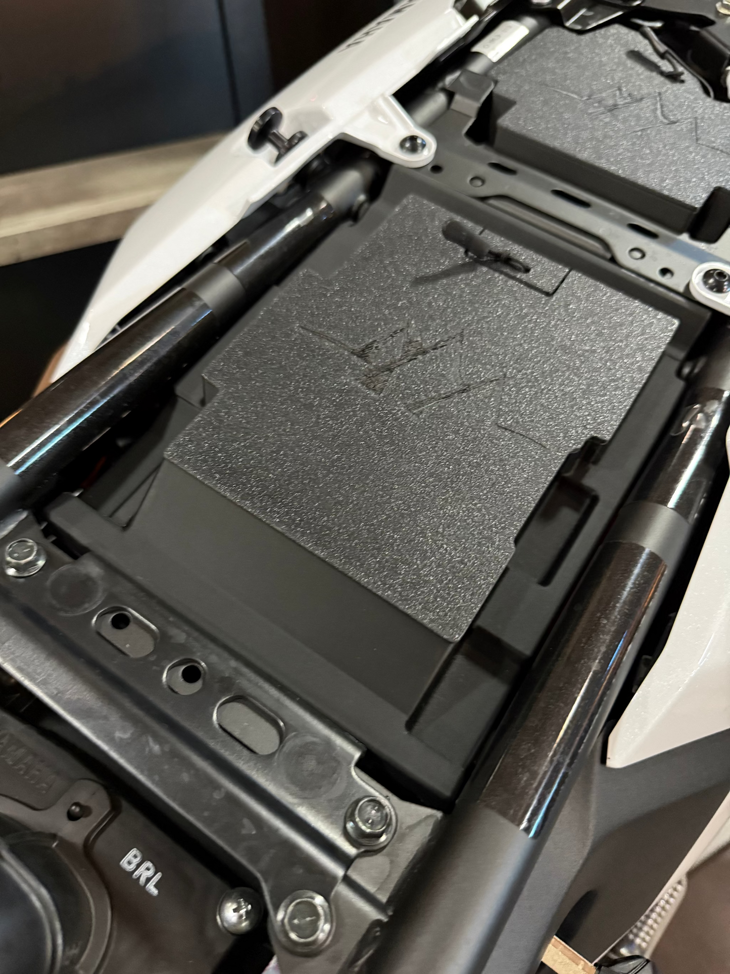MotoCubby Nomad III installed under the rider seat of a 2025 Yamaha Ténéré 700 — close-up showing the box seated in the under-seat space