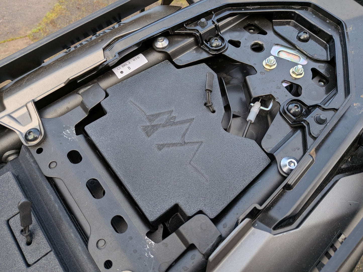 MotoCubby Nomad III installed under the rider seat of a 2025 Yamaha Ténéré 700 — stock antenna location, box and lid seated in the under-seat space