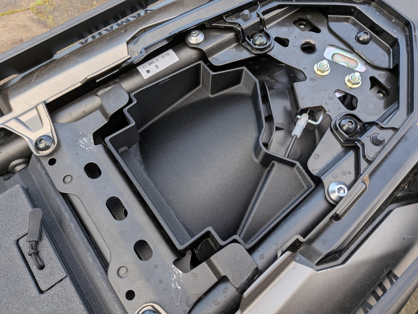 MotoCubby Nomad III installed in a 2025 Yamaha Ténéré 700 — empty box body showing the under-seat compartment with the Bluetooth antenna in its stock location